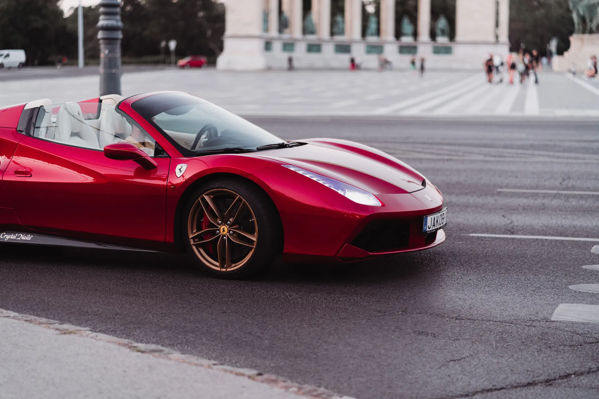 Czerwone Ferrari 488 Spider z opuszczonym dachem na miejskim placu