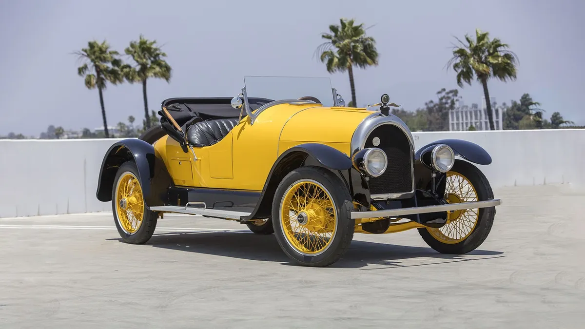 Żółty przedwojenny roadster Kissel ze złożonym dachem, w tle palmy